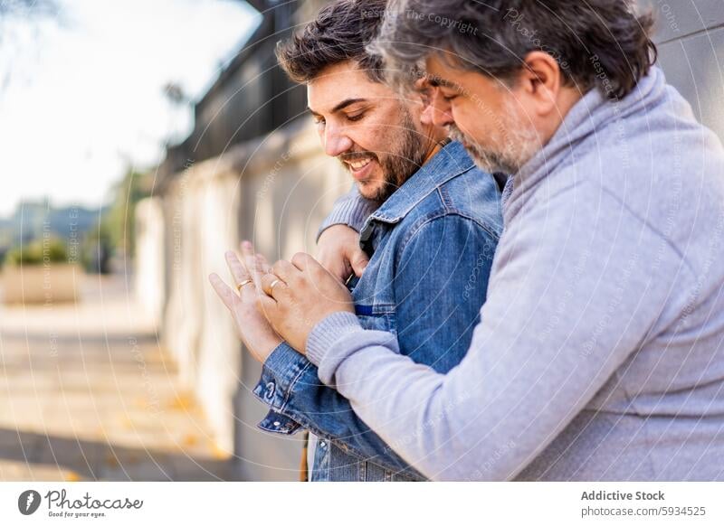 Gay couple enjoying a heartfelt moment outdoors gay love commitment ring wedding affection embrace hugging tender male happiness smiling casual clothing jean