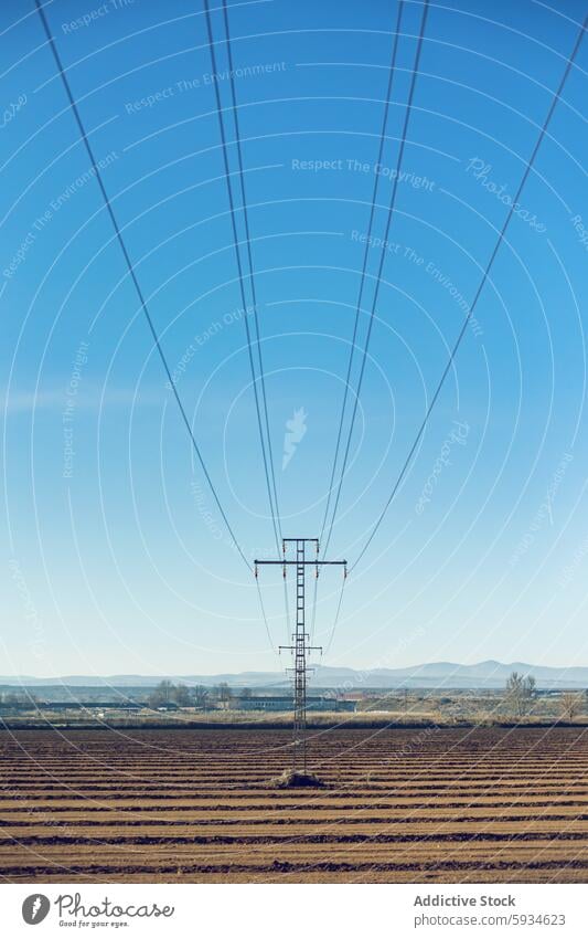 High voltage power lines over rural landscape electricity high voltage infrastructure energy supply transmission electric pole field clear sky