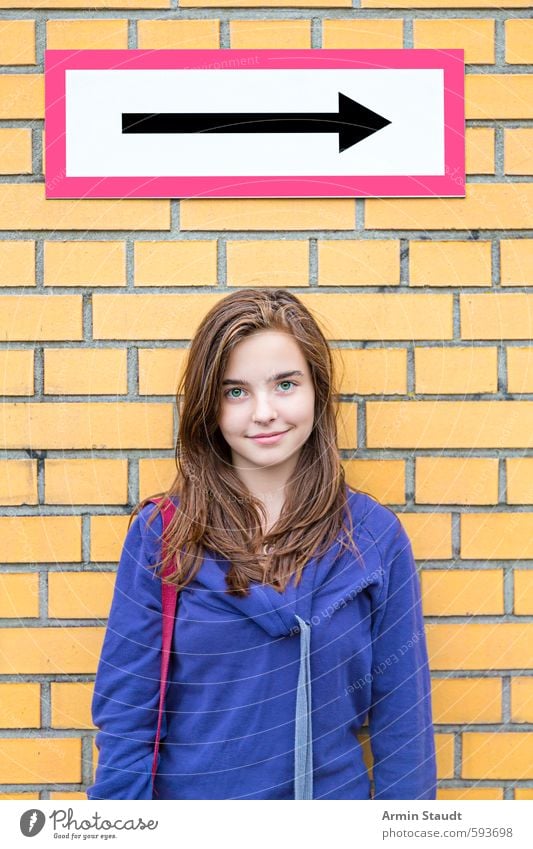 Smiling girl in front of a brick wall/direction arrow Lifestyle Human being Feminine Woman Adults Youth (Young adults) 1 13 - 18 years Child Wall (barrier)