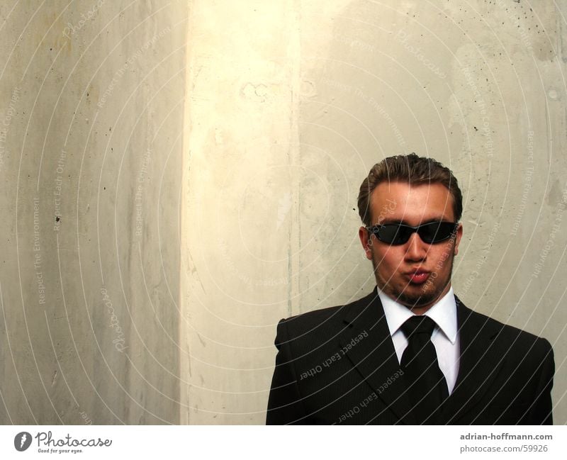 "Küsch misch" Man Fellow Gentleman Fine Suit Black Sunglasses Kissing Lips Pointed Grimace Facial hair Concrete Gray Wall (building) Ridiculous Strange Stupid