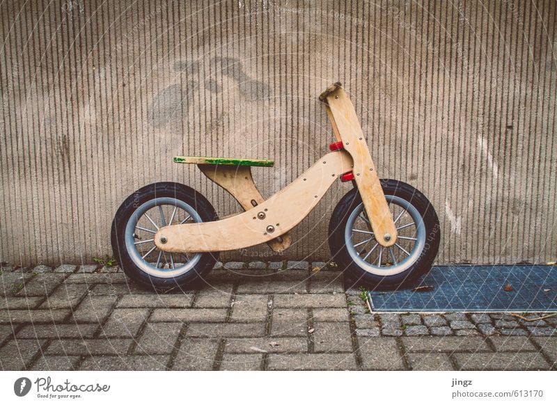 The dog's bike Playing Bicycle impeller Deserted Wall (barrier) Wall (building) Facade Toys Sign Graffiti Stand Wait Funny Cute Yellow Gold Gray Green Red Joy