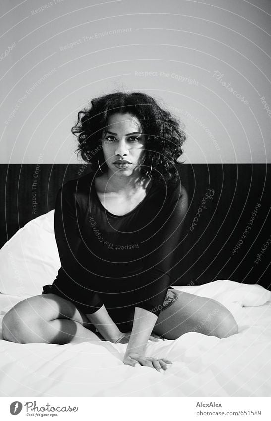 black and white portrait of a young dark skinned woman on a hotel bed Bed Young woman Youth (Young adults) Face Lips Legs 18 - 30 years Adults Dress