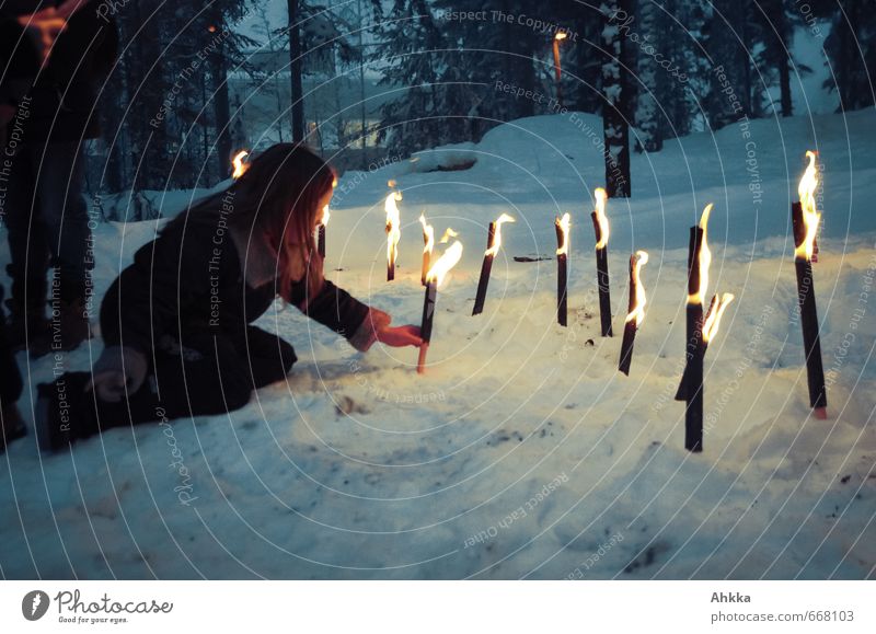 A girl sticks a burning torch in the snow next to other burning torches Human being Girl Infancy Light Trust Life Snow in common Moody Honor Protection Sympathy