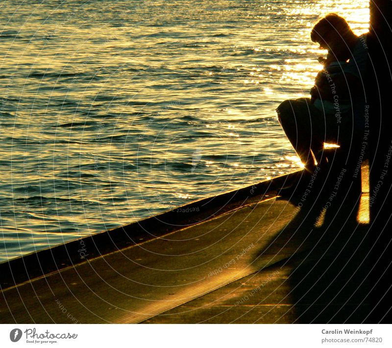 Father and son Light Waves Man Sunset Dusk Harbour Evening Life Water Shadow Jetty Edge Copy Space left Mole Back-light Warm light Sit Silhouette Ambience