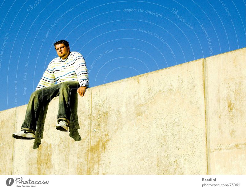 On the wall, on the lookout... Wall (barrier) Man Relaxation Break Sky blue Far-off places Jump Sweater Dangle Summer Waiting room Wall (building) Border