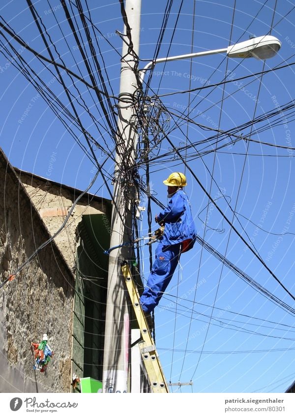 tangled cables Fitter Suva Insecure Helmet Yellow Working clothes Muddled Electricity Bolivia Chaos Electricity pylon Lantern South America Working man Distress