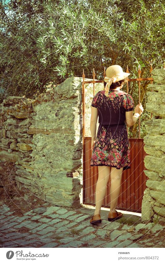 garden gate Human being Feminine Young woman Youth (Young adults) Woman Adults 1 Garden Garden door Entrance Olive tree Dress Hat Wall (barrier) Arise Undo