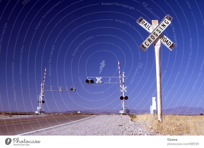 somewhere in Arizona. Steppe Control barrier Railroad tracks White Asphalt Grass Dry Traffic light Railroad crossing Transport Street sign USA Desert