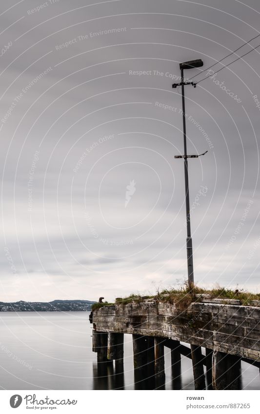 footbridge Water Coast Ocean Lake Dark Footbridge Jetty Calm Loneliness Street lighting Gray Clouds Colour photo Exterior shot Copy Space left Copy Space top