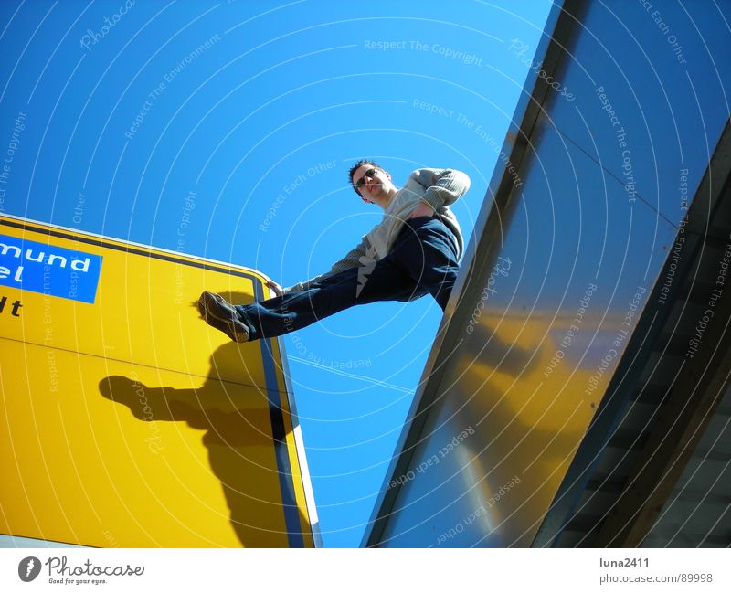 landmark ... Street sign Garage Roof Yellow Man Outstretched Easygoing Signs and labeling Road marking Signage Blue Sky Shadow Legs