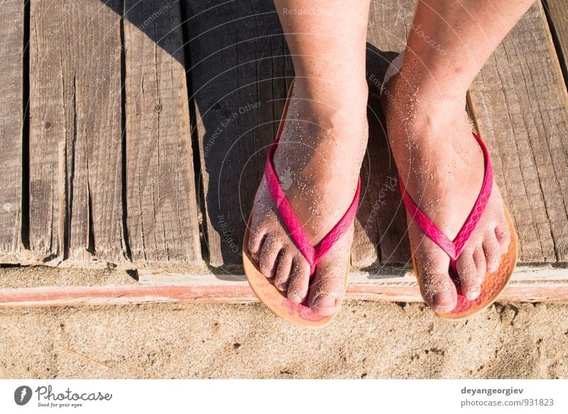 Foto de Young girl legs and flip-flop on the sand beach in summer do Stock