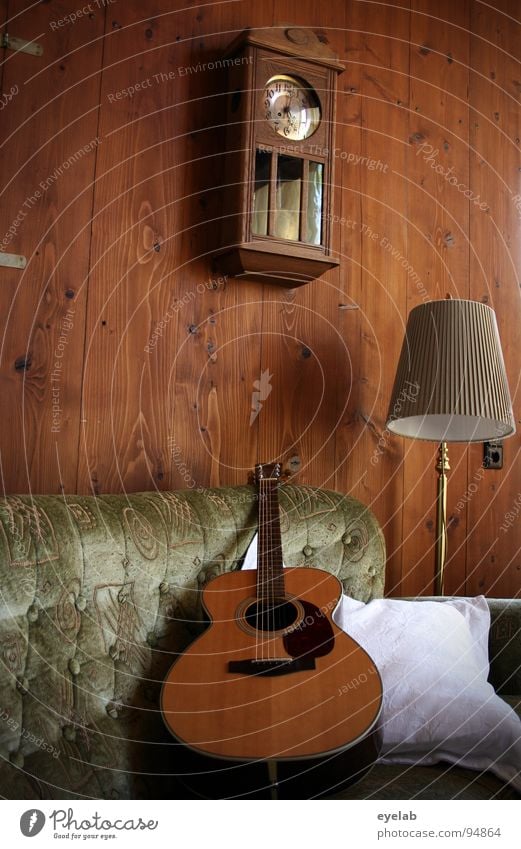 Cosiness is not a question of attitude Wall (building) Wood Wall panelling Western guitar Sofa Seating Comfortable Lamp Standard lamp Wall clock Clock Analog