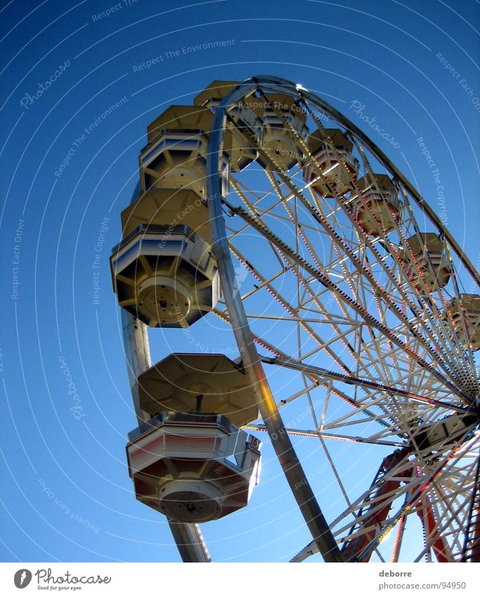Looking up at  a ferris wheel with a blue sky behind. Yellow Ferris wheel Large Fairs & Carnivals Carousel Round Things Blue Joy Tall Circle
