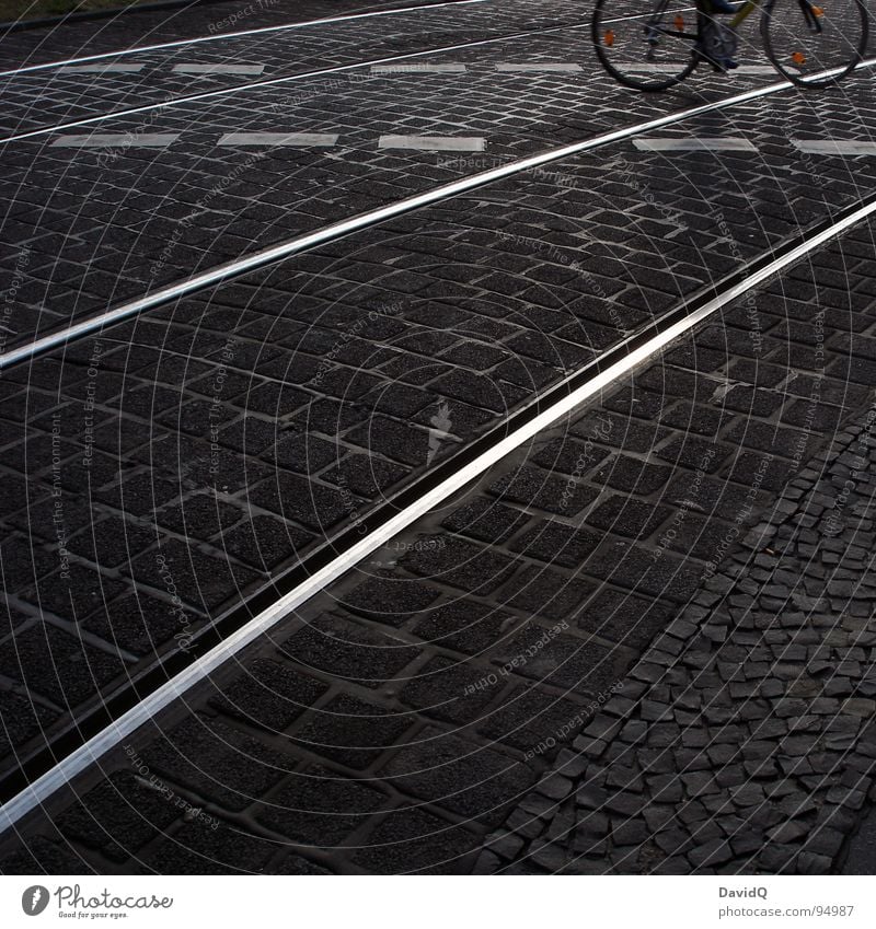 18:07 Asphalt Cobblestones Cycle path Railroad tracks Bicycle White Gray Black Home Closing time Traffic infrastructure Black & white photo Street