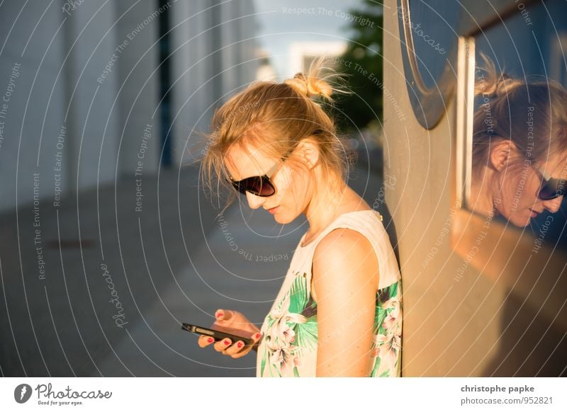 Blonde woman with cell phone standing against wall Leisure and hobbies Trip City trip Cellphone PDA Human being Feminine Young woman Youth (Young adults) 1