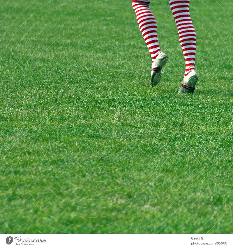 A girl with colorful striped stockings stands on the shadow of a